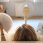 Middle-aged woman in front of 3 fans experiencing a hot flash