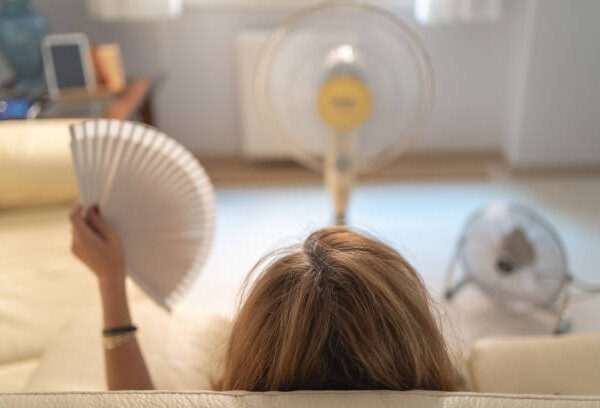 Middle-aged woman in front of 3 fans experiencing a hot flash