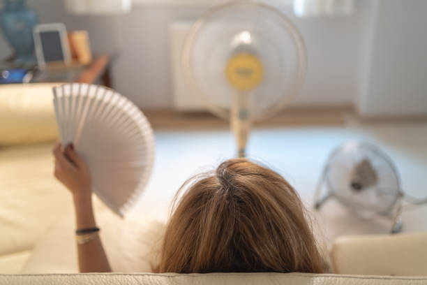 Middle-aged woman in front of 3 fans experiencing a hot flash